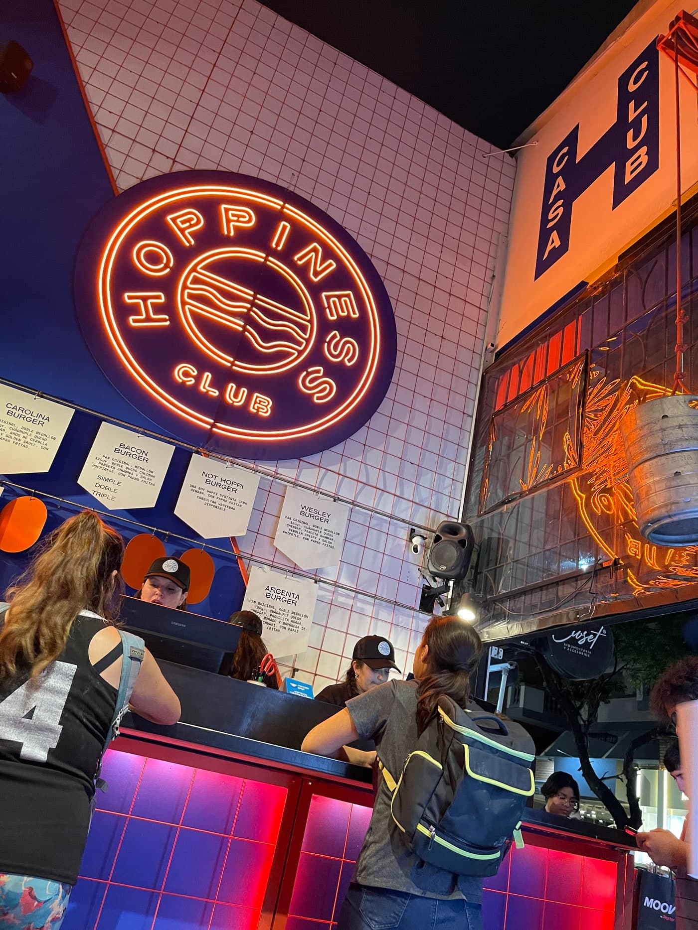 Cartel de neón de Hoppiness encendido de noche en uno de los clubes